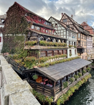 Old building on canal covered in ivy and flowers