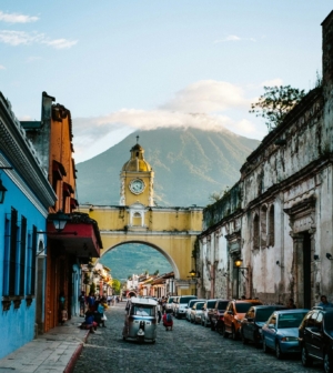 Street in Guatemala with yellow arch and Volcano in background