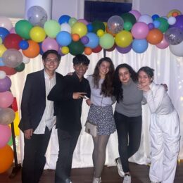 A group of five international students at a cultural event at Wesleyan College. In front of a background with lights and balloons.