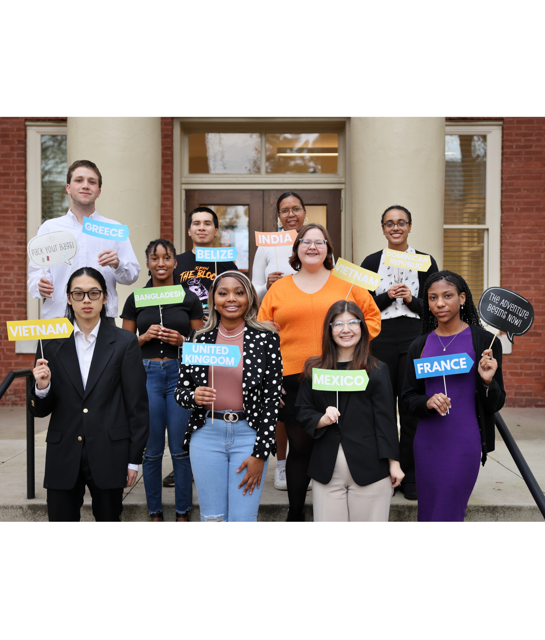 Group of March 2024 Global Leader Scholarship students outside Wiggs Hall with country cards