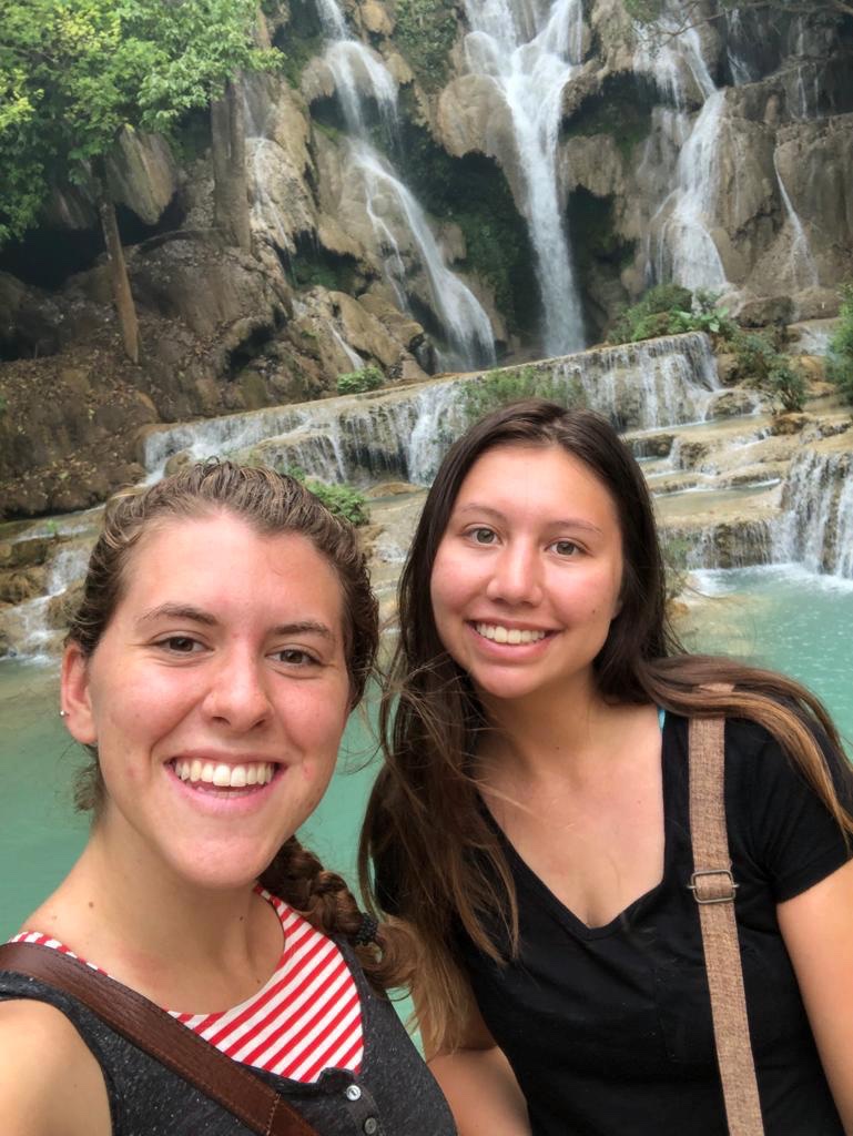 2 female students in front of waterfall.