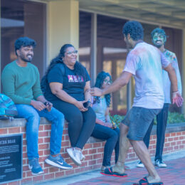 Group of students sitting on wall at Holi